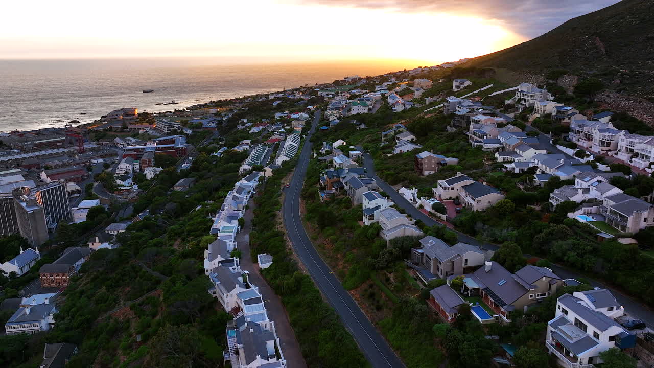 Aerial cinematic drone sunrise Simon's Town small fishing town quite city Cape Town South Africa early sunlight clouds Table Mountain Fish Hook Muizenberg penguins forward movement