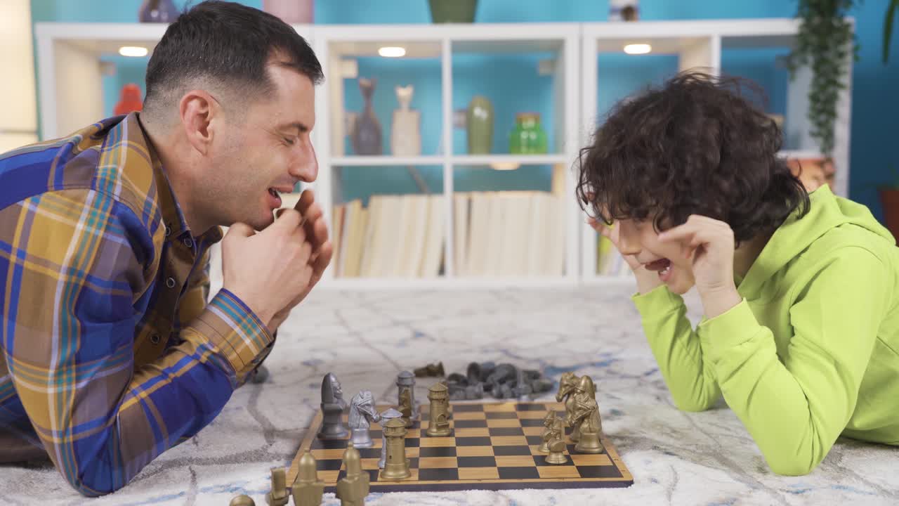 el niño se está preparando para comer a su padre en el ajedrez, se están divirtiendo entre sí.