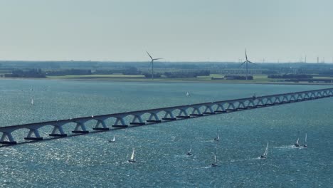 long lens drone shot of the zeeland bridge with a lot of sailboats passing through