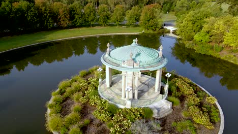 gazebo with stone columns in old fashioned romantic venue surrounded by water - aerial drone orbit establishing view