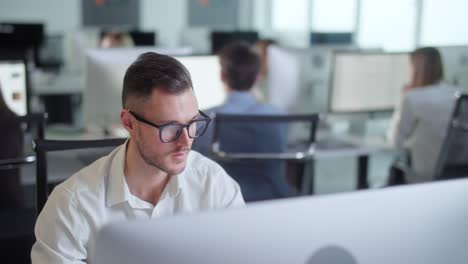 retrato de un joven empresario en una oficina de espacio abierto trabajando en una computadora de cubierta. hombre profesional escribiendo en el teclado de la pc. retrato de hombre de negocios positivo mirando la pantalla de la computadora