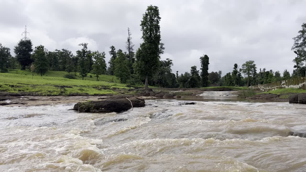 구름이 많은 몬순 날 산악 숲 지역을 가로질러 언덕에서 언덕 아래로 흐르는 강의 드