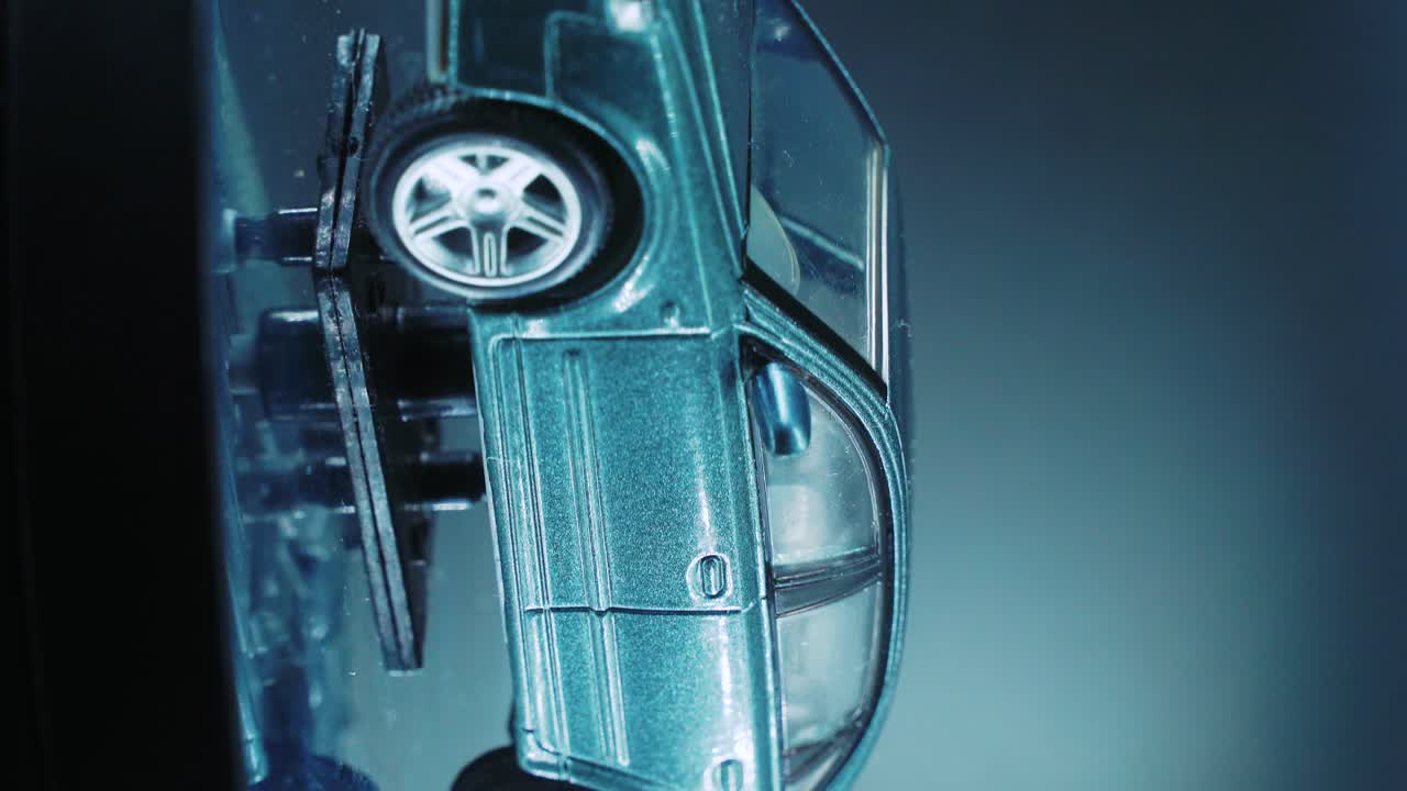 миниатюрная модель металлического образца автомобиля на вращающемся стенде со студийным светом, вертикальная съемка крупным планом, видео 4k, серебристые колеса, черные шины, двери и окна