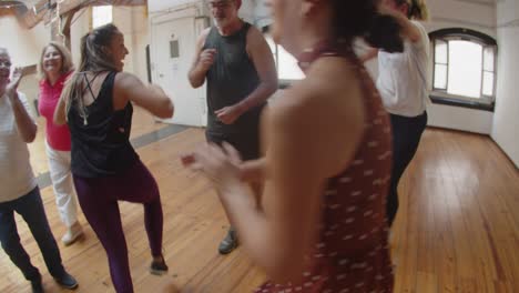 long shot of excited people standing in circle and dancing