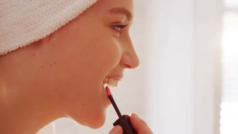 mujer aplicando brillo labial en sus labios en el baño