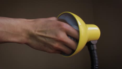 close up of a hand taking a light bulb of a yellow lamp