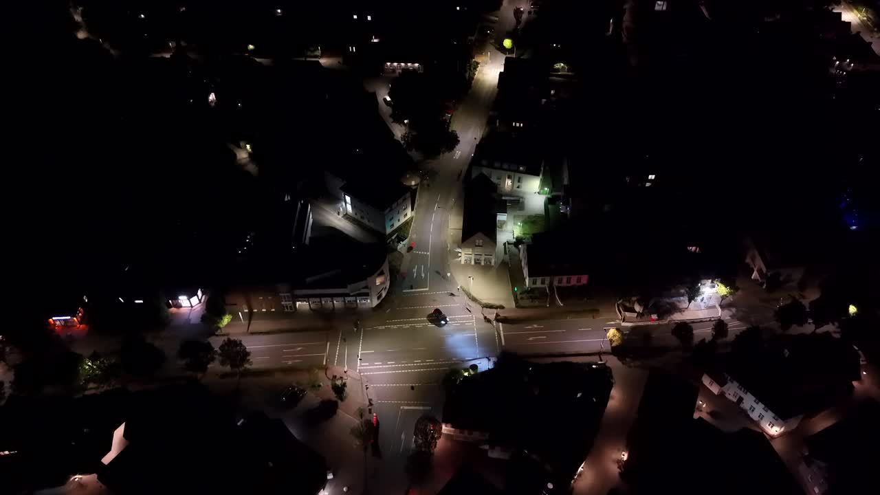 Aerial top down shot of vehicle on junction turning into street of small american town. Clear night sky in summer. Houses and homes in suburb area of USA