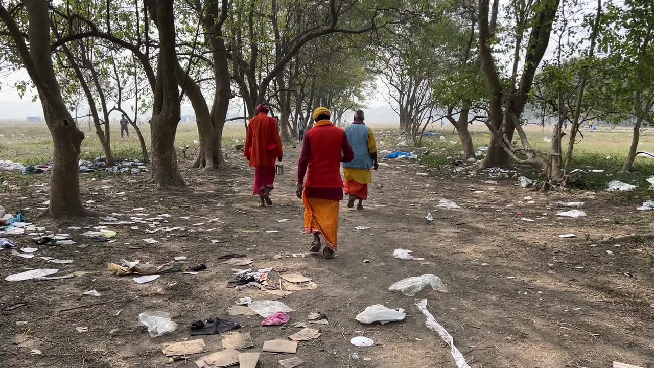Rear view of sadhus walking down the pathway on Maidan for Ganga Sagar mela in Kolkata, India in a winter morning