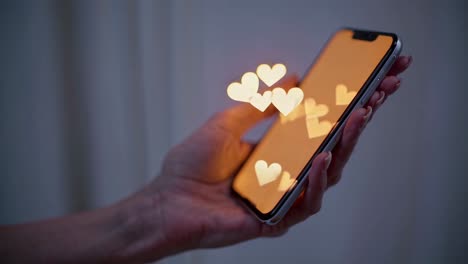 hand holding a smartphone with glowing hearts