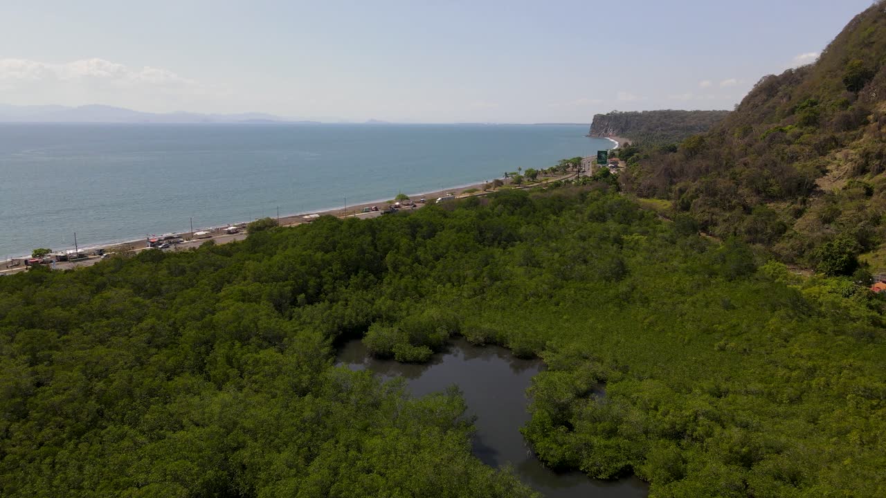 vista aérea de un avión no tripulado sobrevolando un bosque tropical hacia el tráfico de la autopista en port caldera, puntarenas, costa rica