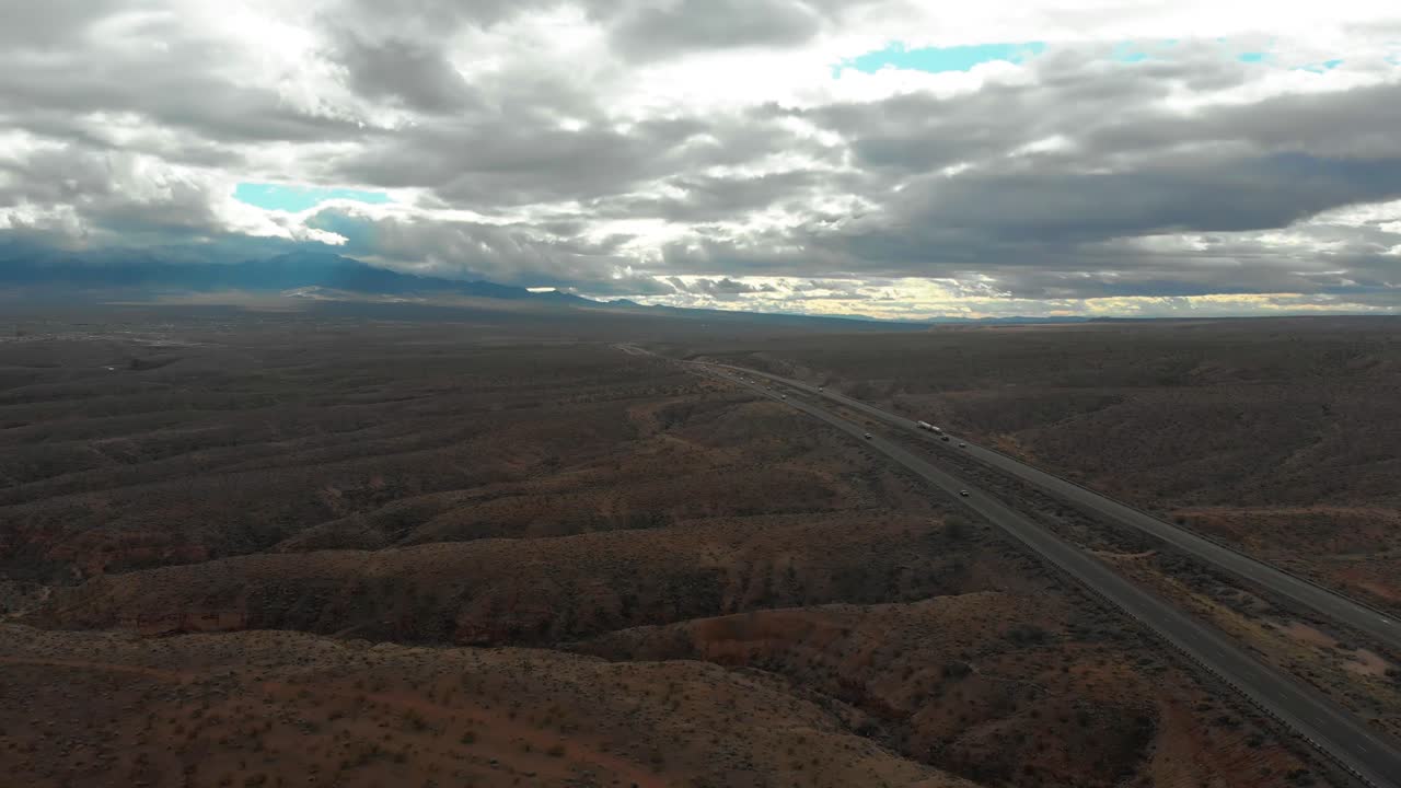 Aerial shot of the Utah deserts on a cloudy day as cars pass on the highway.