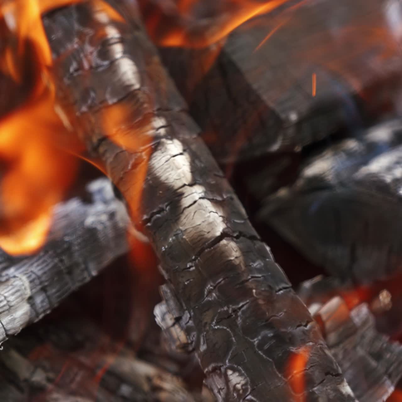Smoldered logs in fire flame. Burning log of wood as abstract background. Hot embers of burning wood in fire. Close-up.