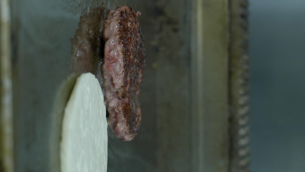 뜨거운 프라이팬에 구운 버거 고기와 할루미의 세로 샷