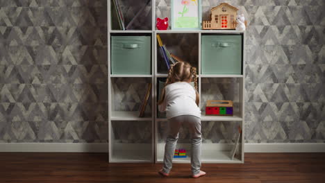 little girl with braided hair looks for toys on special rack