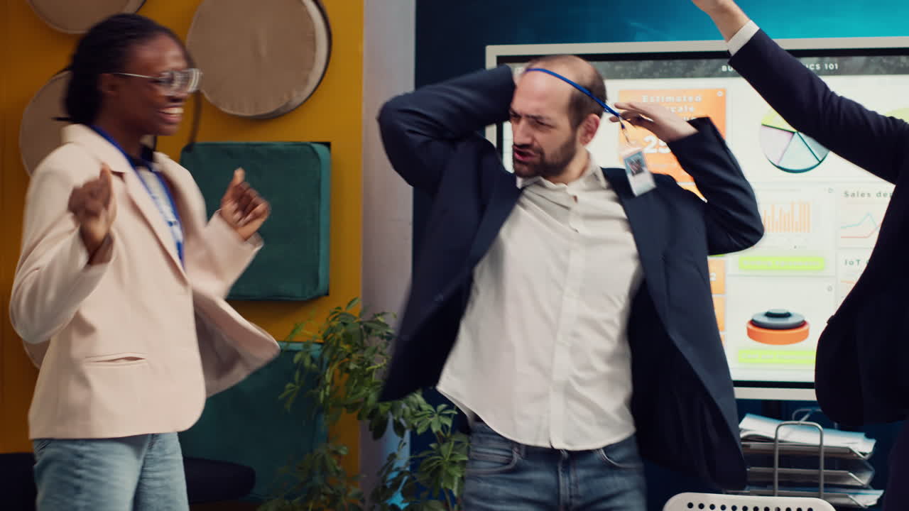 compañeros de trabajo satisfechos bailando en la sala de juntas y celebrando un éxito comercial