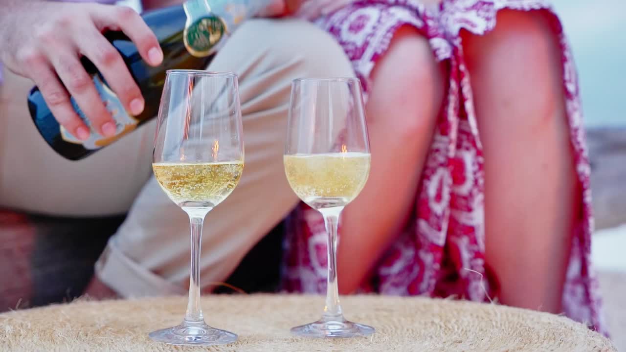 Uomo che versa vino bianco frizzante dalla bottiglia in un classico calice da vino per la sua compagna