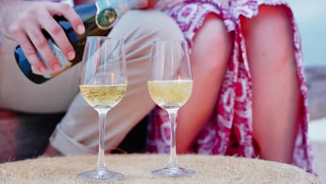 Man-Pouring-Sparkling-White-Wine-From-Bottle-Into-Classic-Wine-Glass-For-His-Lady