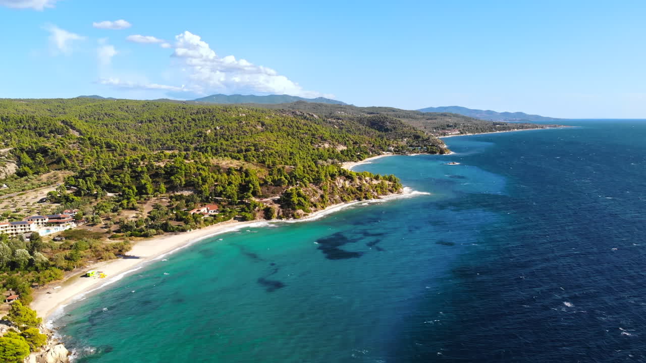 Vista aerea da drone della costa rocciosa del Mar Egeo con vegetazione, città e strada lungo la costa, onde del mare in Grecia