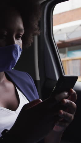 african american woman wearing face mask in car