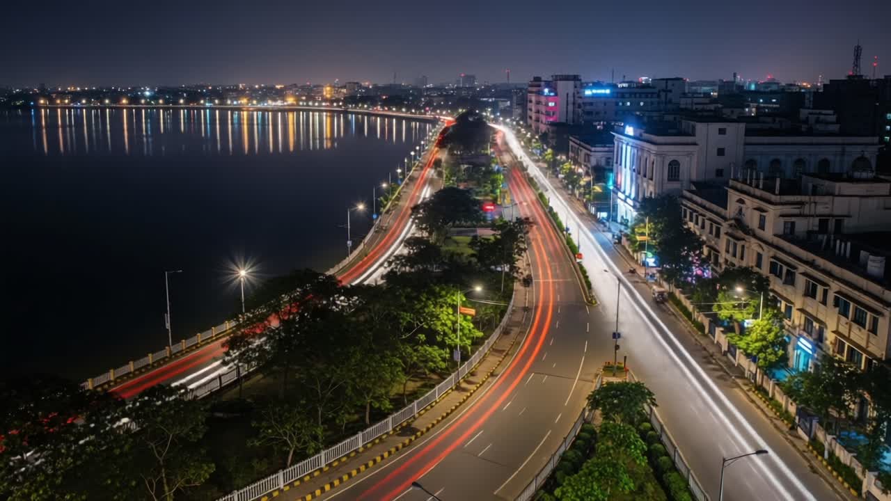 Stunning Aerial View of a Vibrant Cityscape at Night, Capturing Illuminated Roads, Calm Waters, and Lush Greenery in a Beautiful Urban Setting