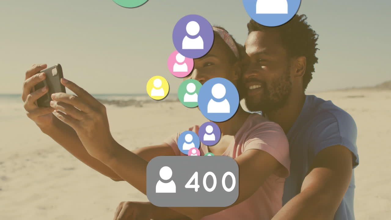 Taking selfie on beach, couple with animation of social media icons visible