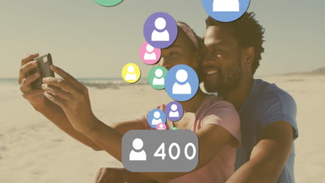 taking selfie on beach, couple with animation of social media icons visible