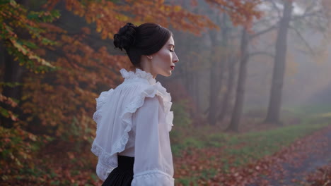elegant woman in historical dress in a misty autumn forest