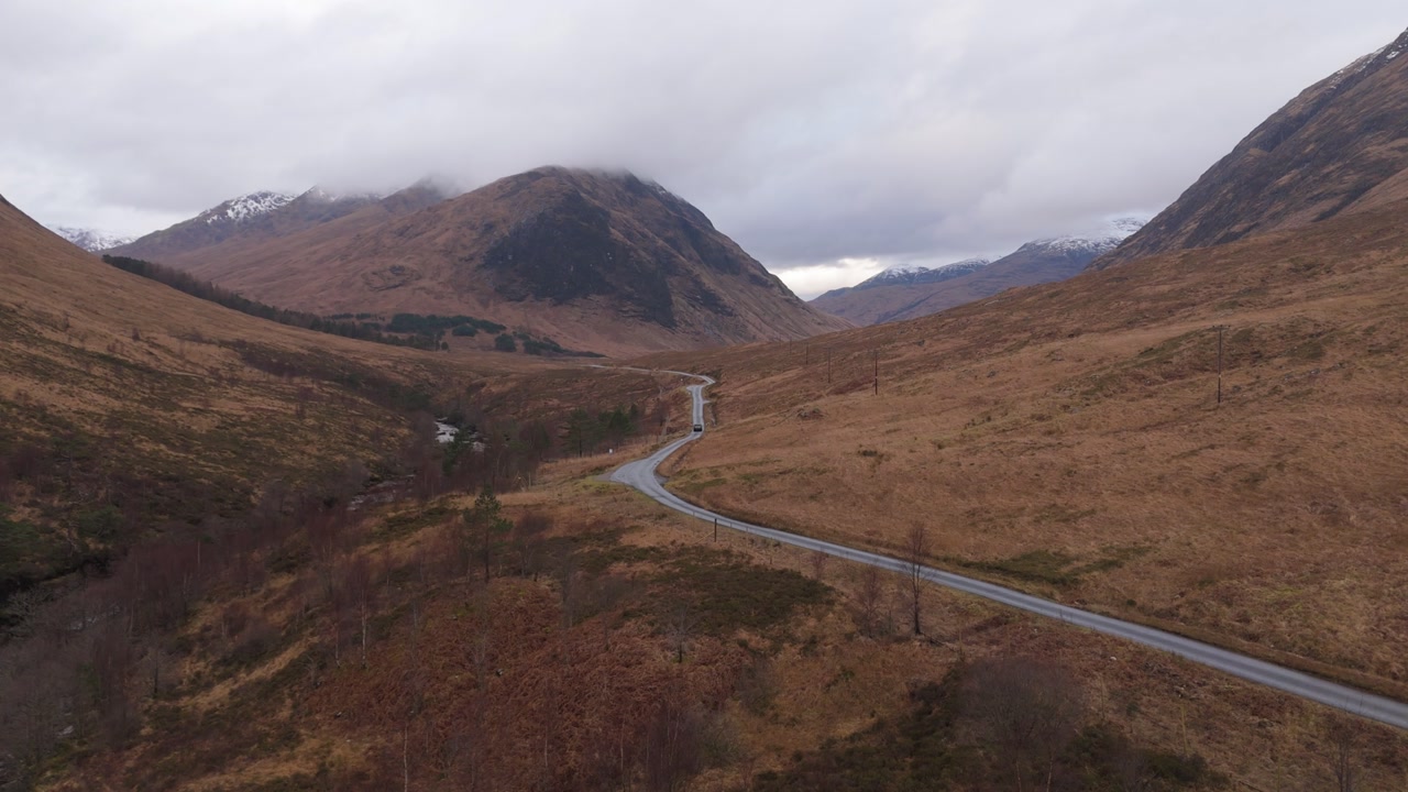 view of car driving away in scotland with view of highlands