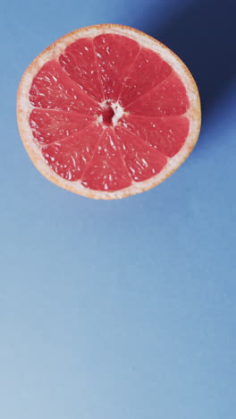 vertical video of halved red grapefruit with copy space over blue background