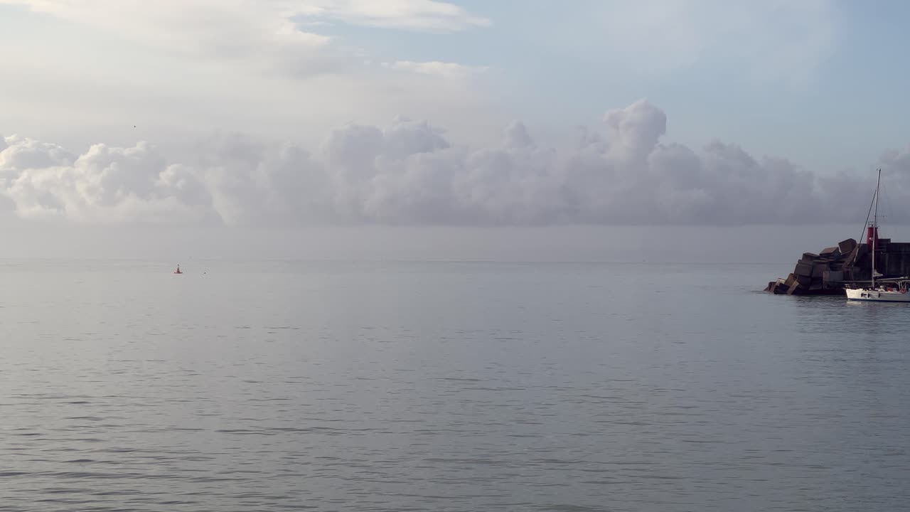 Static view of a sailboat sailing near a lighthouse. Daylight