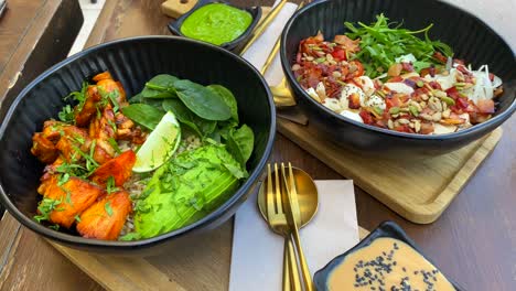 Tasty-healthy-green-salads-in-a-bowl-with-chicken,-avocado,-lettuce,-crispy-bacon-and-microgreens-with-salad-dressing,-lunch-time,-4K-shot