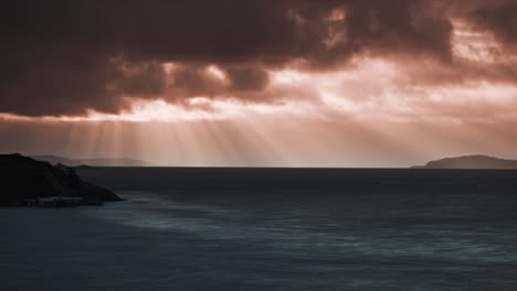 the orange and pink tones of sunset reflect on the water as the sun disappears behind norwegian islands