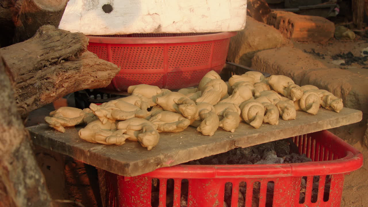 Un mucchio di flauti di argilla tradizionali a forma di animale su un'asse di legno nel villaggio della ceramica di Thanh Ha, Vietnam, che mostra l'arte della ceramica tradizionale