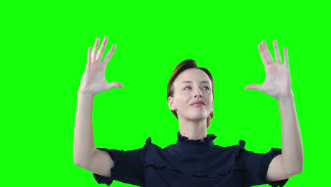 mujer caucásica levantando las manos sobre un fondo verde