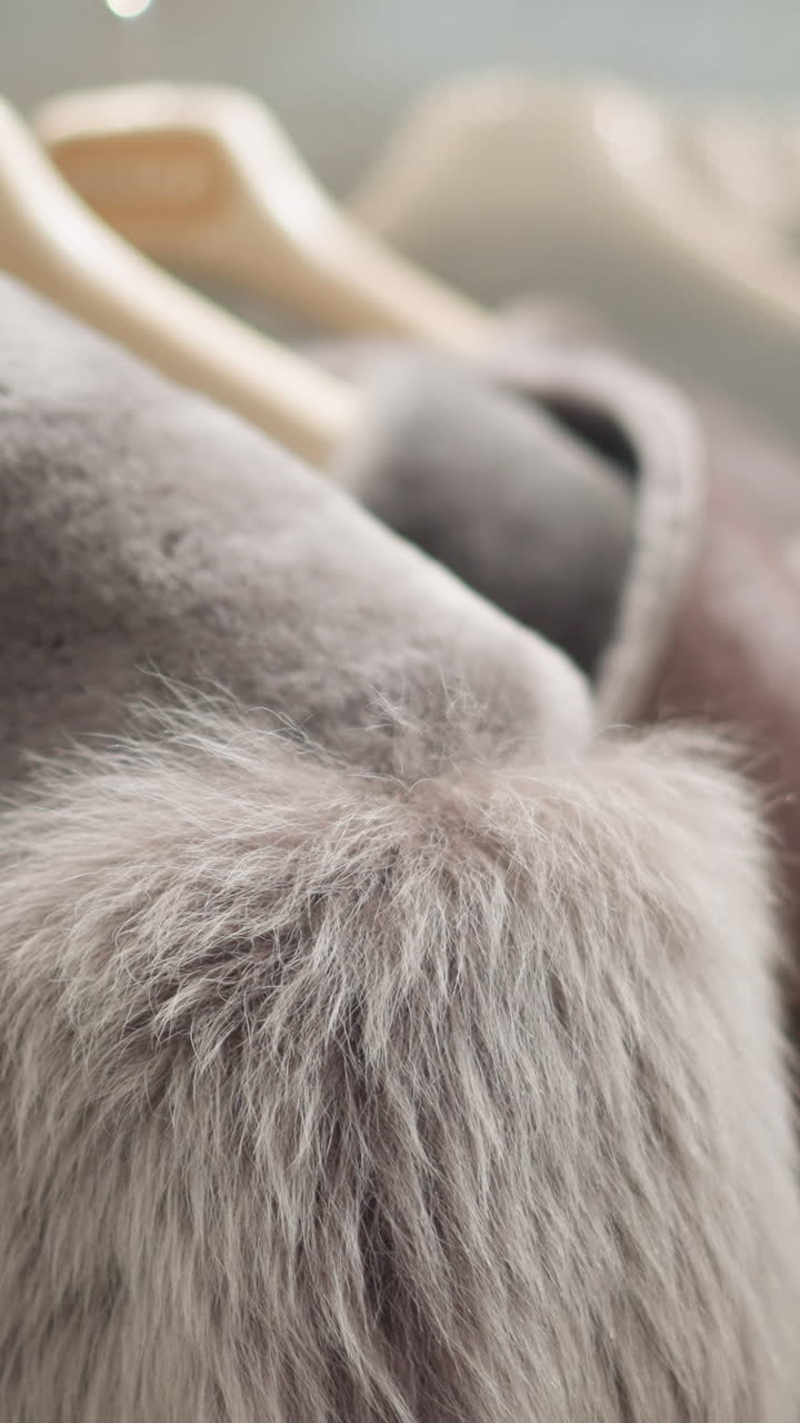 부드러운 털 목걸이를 가진 사치스러운 갈색 재이 잘 조명 된 현대 가게에서 나무 개에 매달려있는 클로즈업. 흐릿한 배경으로 우아한 텍스처를 보여줍니다.