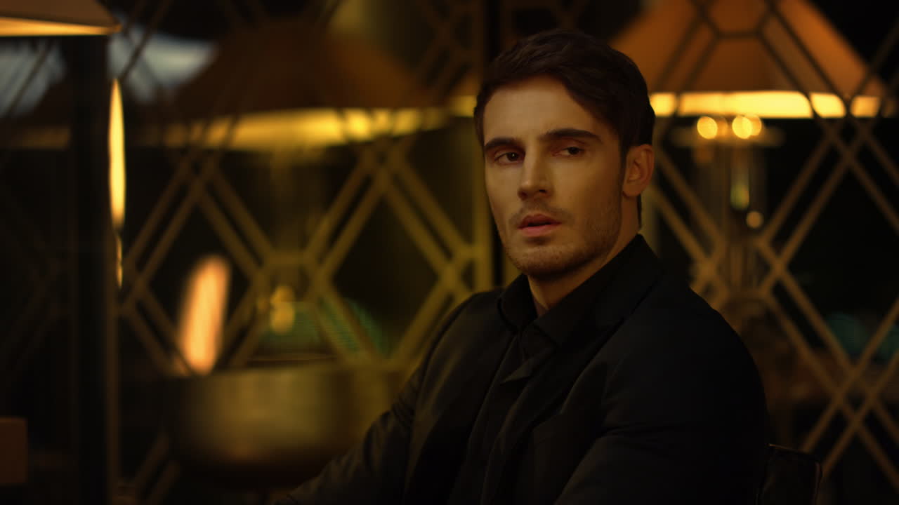 jefe de traje negro sentado en una silla en el interior. hombre serio mirando a un lado.