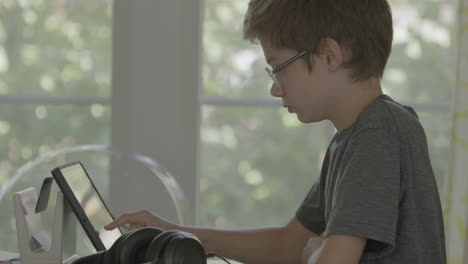 Cute-boy-at-home-at-dining-room-table-working-on-an-iPad