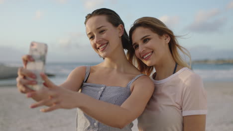 Dos-Hermosas-Mujeres-Jóvenes-Tomando-Fotos-Selfie-En-La-Playa-Usando-El-Teléfono