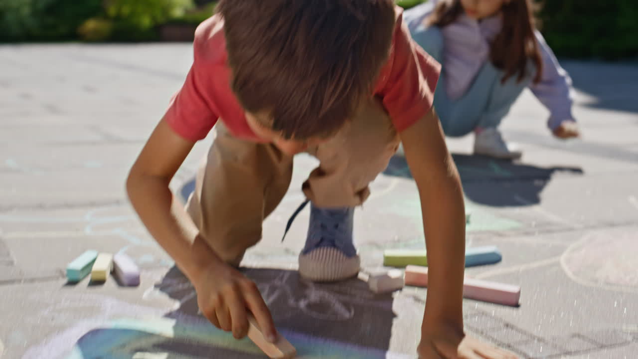 Small kids drawing chalk at sunny playground closeup. Friends creating pictures
