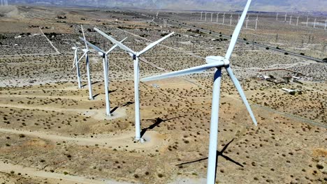 Cool-sweep-down-line-of-spinning-blades-of-windmills,-wind-turbines-energy,-green,-renewable,-huge-power-generating-farm,-desert-hills,-aerial-4k-drone-L-to-R,-Palm-Springs,-Coachella,-Cabazon,-Calif