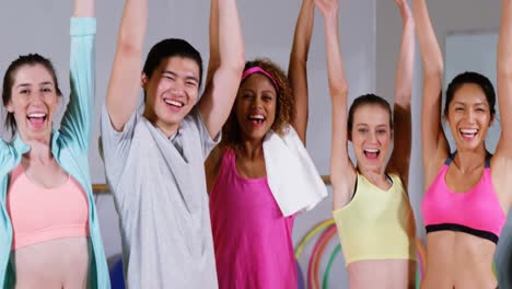 group of fitness team posing with arms up in fitness studio