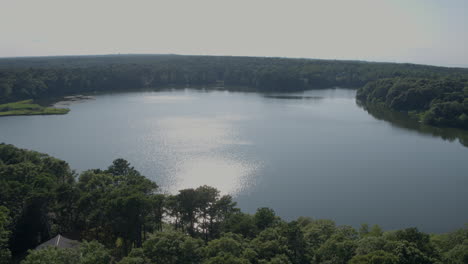 aerial pull away from pond in cape cod and descent over trees and woods