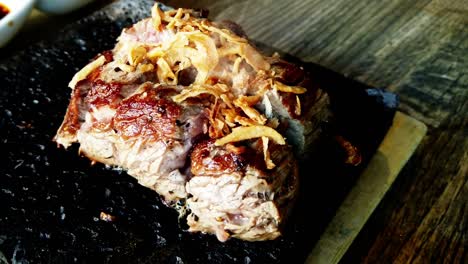 bistec japonés de primer plano que se cocina en una roca de lava con una panorámica de 180 grados mientras la carne orgánica de kobe se autococina y se cubre con cebollas humeantes sala caliente para el texto en un plato cuadrado de madera entre tradicional