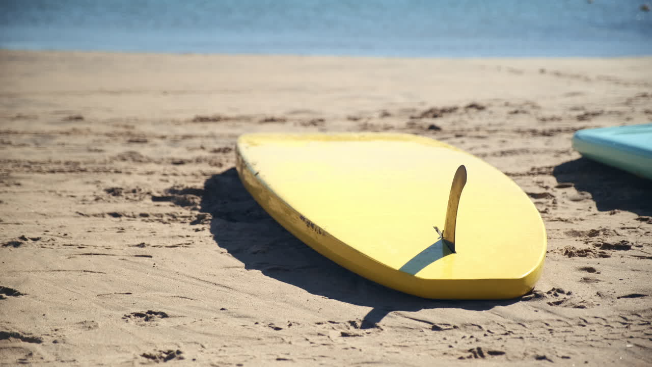 tabla de surf en la playa de arena de santa monica california, con olas del océano en el fondo