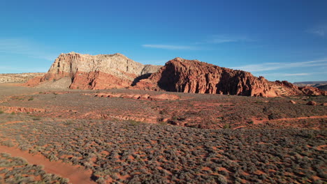 a stunning aerial view of towering red rock formations amidst arid desert terrain under a vibrant blue sky, showcasing the rugged natural beauty of utah.