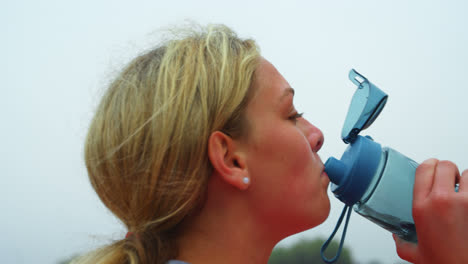 Side-view-of-Caucasian-female-athlete-drinking-water-at-sports-venue-4k