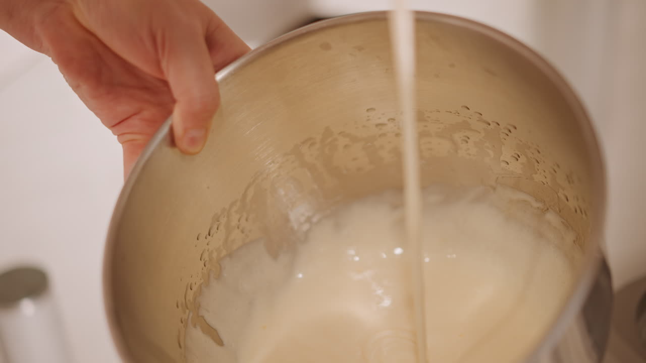 Sbattendo la crema per la torta di zucca in una ciotola, un pasticcere che pratica una sbattitura di precisione, monitorando la consistenza e la densità di versamento, regolando il rapporto tra latte e spezie, illuminazione brillante della cucina di prova con un primo piano.