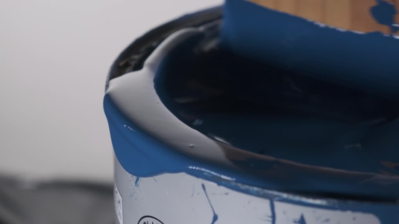 primer plano de tablón de madera revolviendo y derramando pintura azul