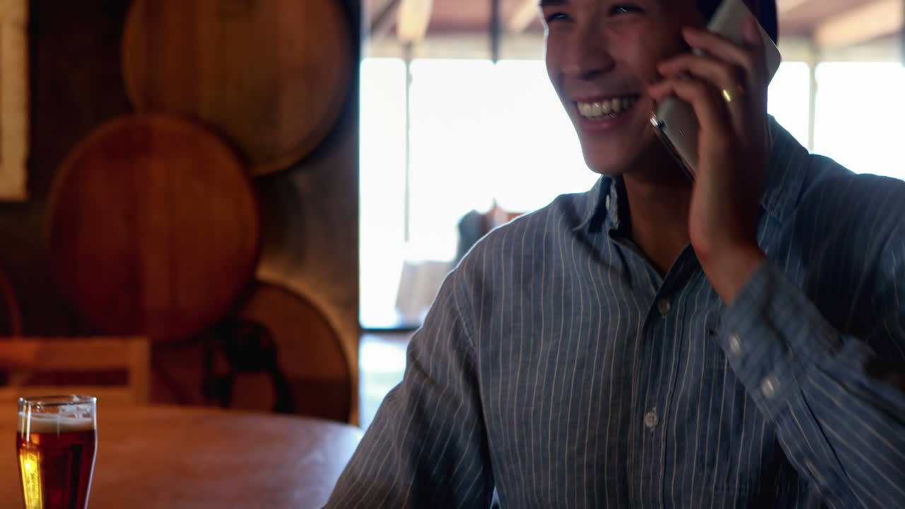 레스토랑 4k에서 휴대 전화로 이야기하는 동안 맥주를 마시는 사람