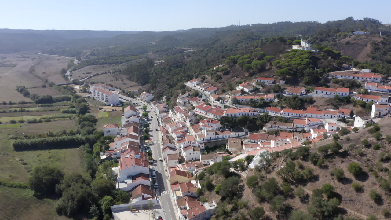 Volo con drone aereo verso le colline con vista sulla città ad Aljezur, Algarve, Portogallo.